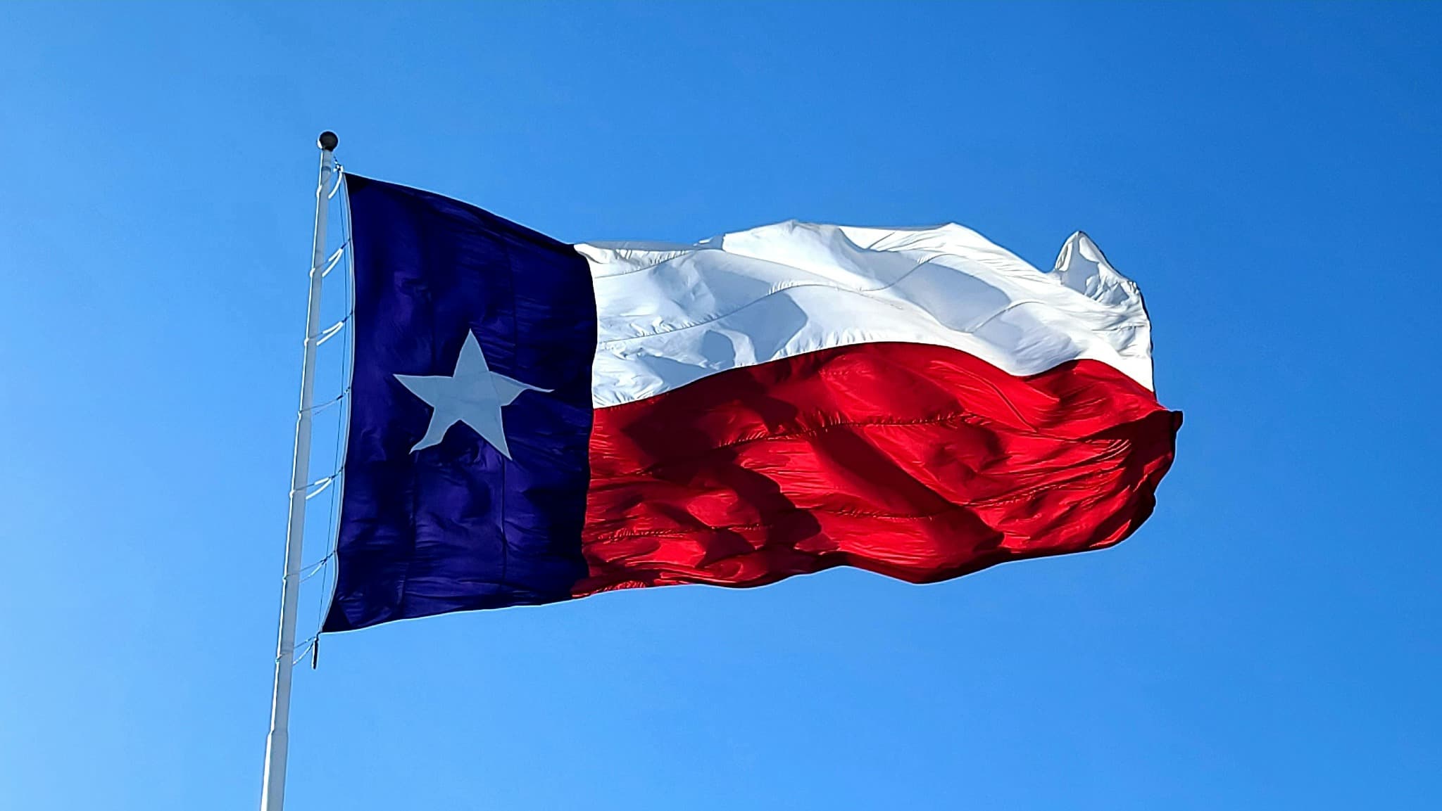 Texas flag flying against a blue sky